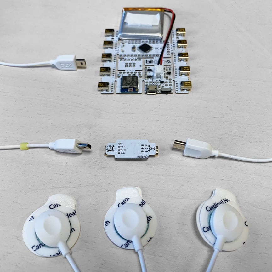 The BITalino kit laid out: board with battery, EMG sensor module, two cables, three pre-gelled electrodes