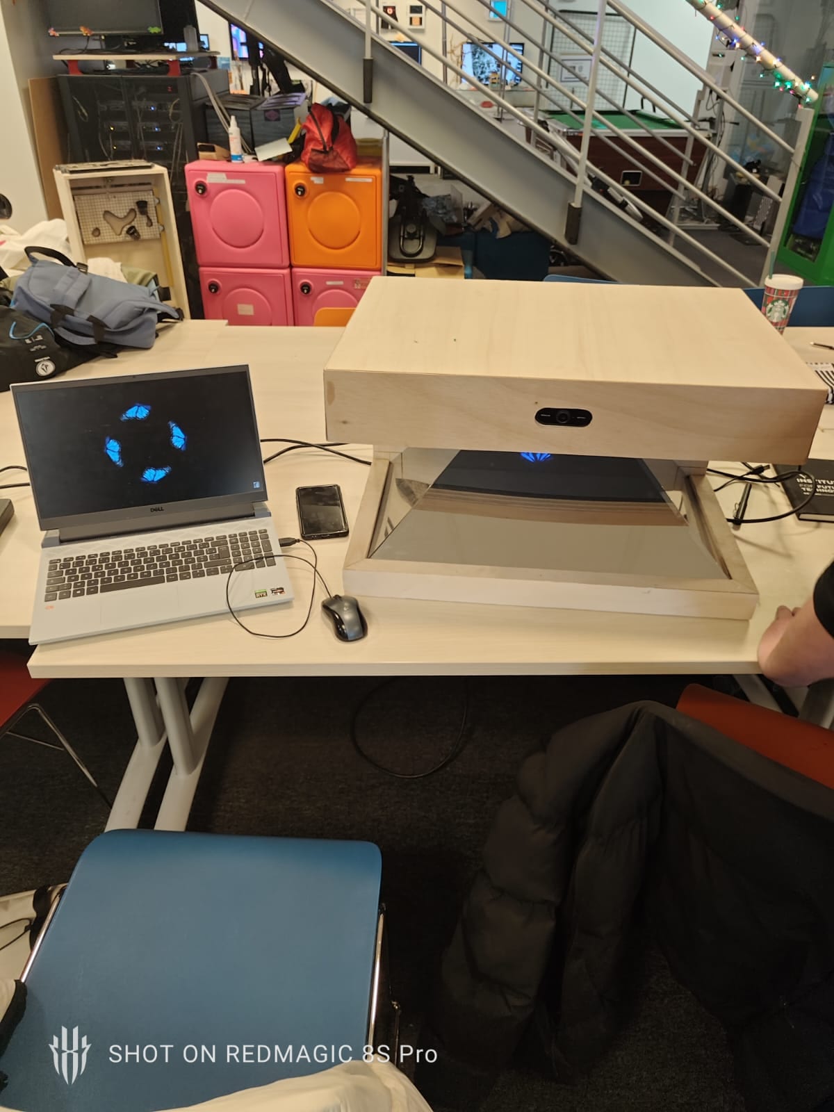 The hologram unit on a workbench next to a laptop