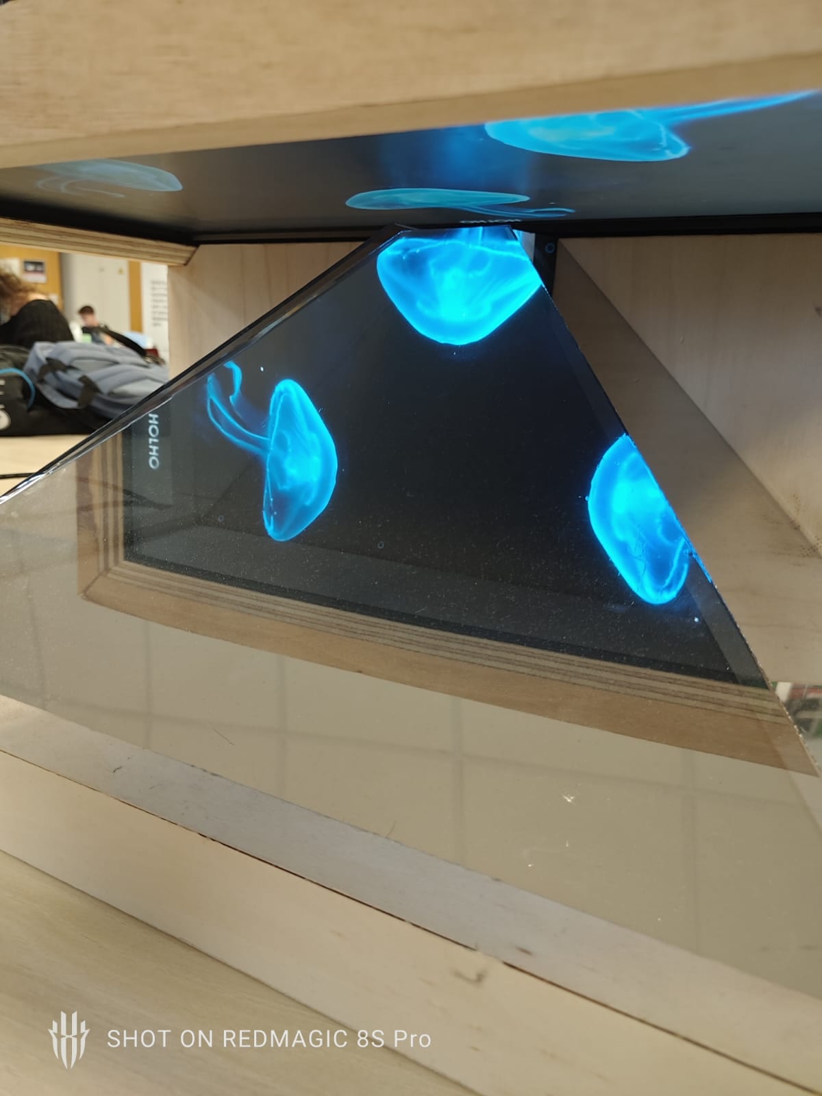 Three luminous blue forms reflected in the faces of the pyramid